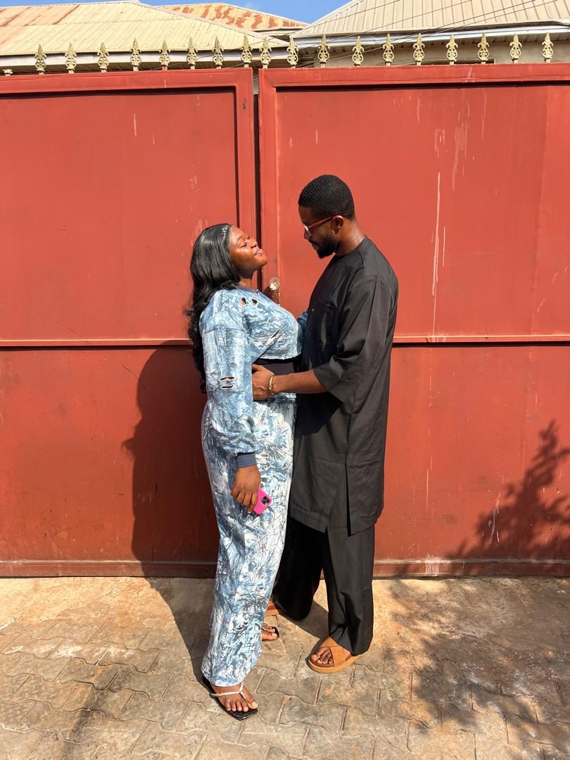 Nnenna looking up at Chukwuma in front of a red gate