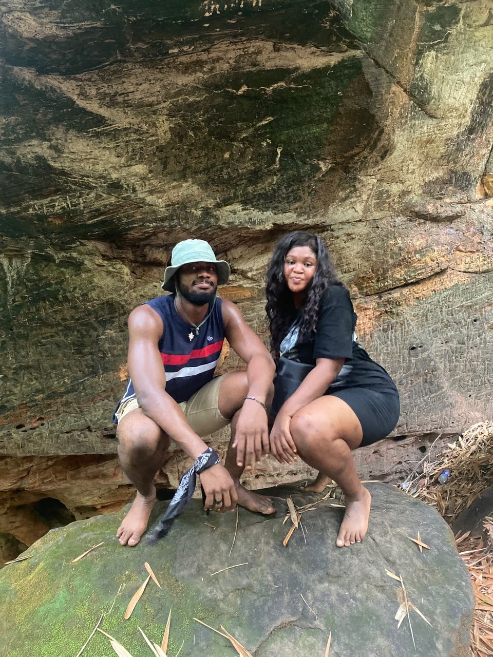 Chukwuma and Nnenna crouching together beneath a rock overhang